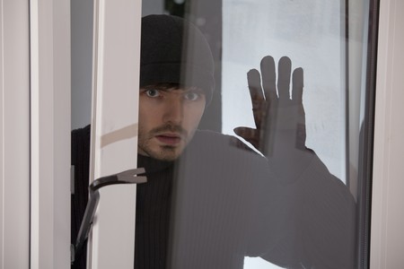 burglar with crowbar looking into the windowの写真素材
