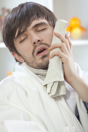 sick man with painful toothache on the sofaの写真素材