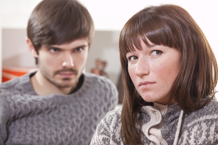 frustrated man looking at unhappy woman in apartmentの写真素材