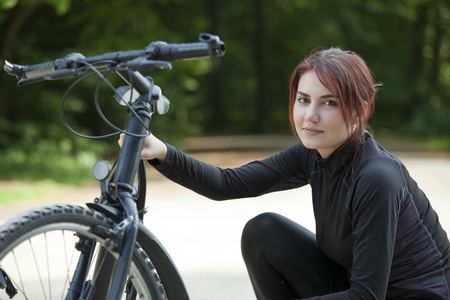 young woman having bike problem in parkの写真素材