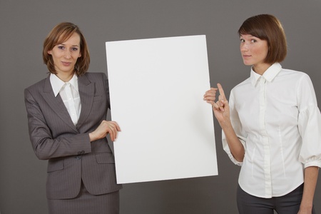 two business women with a white board over grey backgroundの写真素材