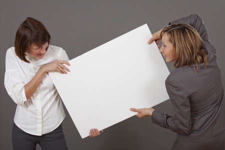 two business women fighting over white boardの写真素材