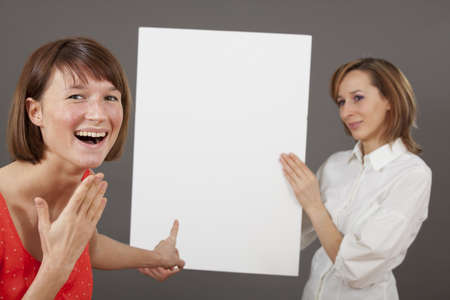 special offer or great deal - happy woman pointing with a finger on blank boardの写真素材