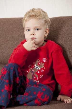 Portrait of young boy sitting on sofa in pyjamaの写真素材