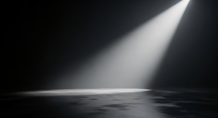 A single, bright spotlight cuts through darkness, casting a dramatic beam onto a wet, reflective stage floor, creating an atmospheric and mysterious mood.の素材