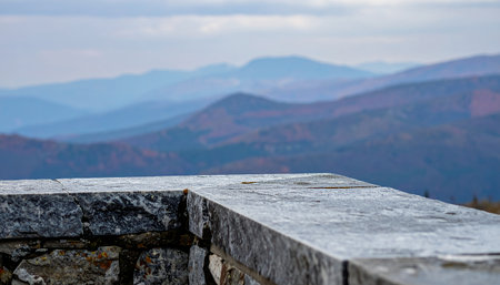 A stone wall and overlook provide a foreground to a vast landscape of rolling blue mountains, hinting at autumn colors.の素材