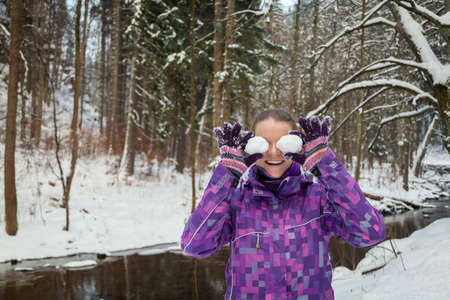 Young woman in snowy forest holding snow in the hands of the sight