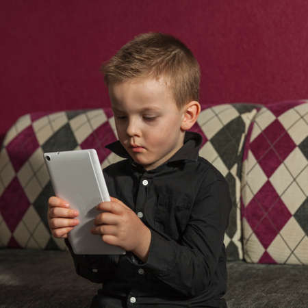 boy in the living room on the couch playing on tabletの写真素材