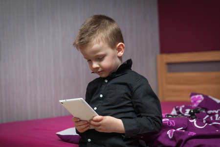 boy in the living room on the couch playing on tabletの写真素材