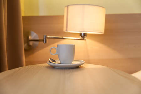 cup of coffee on wooden table at the hotel with a lamp in the backgroundの写真素材