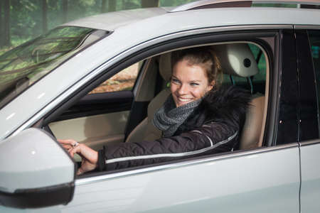 A woman in her new white big car enjoys the first ride
