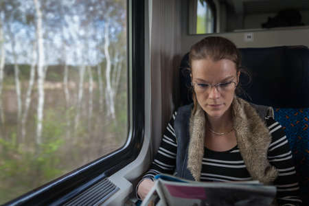 The young woman is on the train and watches through the window on the outsideの写真素材