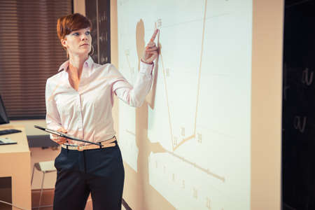young female student and businessman showing the results on a graph on a blackboard in a classroomの写真素材