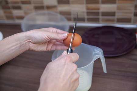 woman preparing cake from flour and eggs. He breaks the egg and separates the egg white from the...