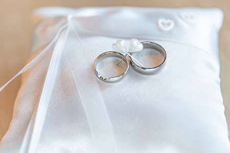 Golden wedding rings on white pillow ready for ceremony. The newlyweds will exchange their rings and say their promise.の写真素材