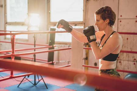 Young woman prepares for matches MMA in the cage. Training in a sport hallの写真素材