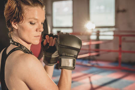 Young woman prepares for matches MMA in the cage. Training in a sport hallの写真素材