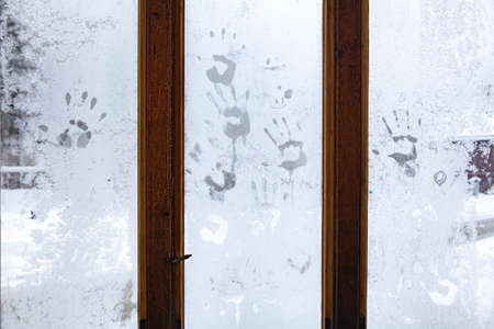 Window in the room covered with frosty mosaic in winter. Frost patterns on glass. Handprintsの写真素材