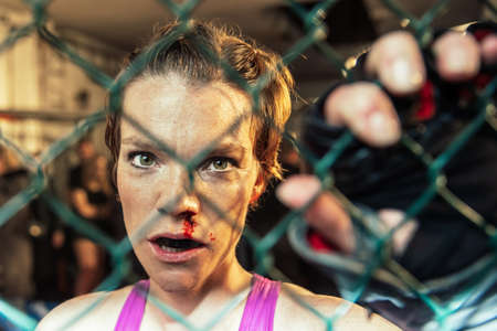 Gorgeous woman, mma fighter in gym during training. Preparing for a hard caged match. Sexy fighter girl punching actively. Aggressive and ready to fight.の写真素材