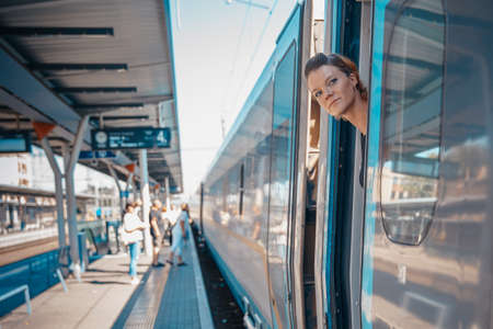Young attractive woman bussinessman says goodbye to a boarder on train train. He enters the train with his luggageの写真素材