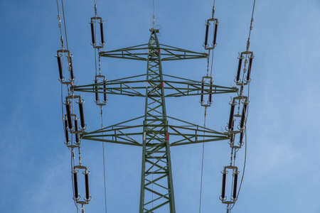 High voltage power lines through fields and meadows they supply power to towns and villages