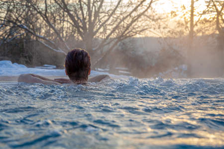 young pretty attractive woman enjoying wellness with sauna and swimming pool outdoors in winterの写真素材
