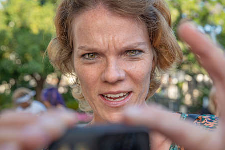 A girl shoots a video of the sea on a small camera. A woman in a hat shoots a video on an action...