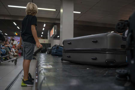 boy is waiting for luggage at the airport upon arrivalの写真素材