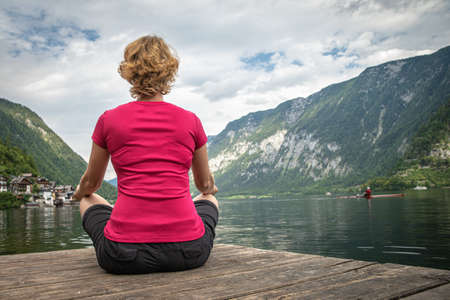 A young woman relaxes with a view of a mountain lake after a busy hikeの写真素材