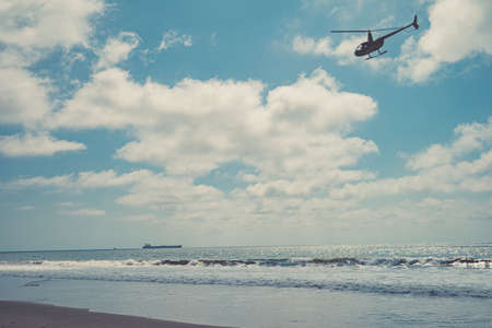 Helicopter patrols over the ocean beachの写真素材