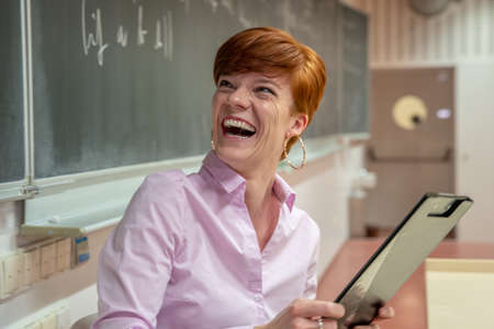 Young teacher lectures at the School of Mathematics, writes chalk on a blackboardの写真素材