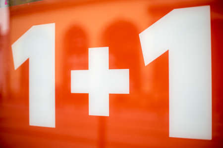 white headline 1 +1 on a red background when sold in a shopの写真素材