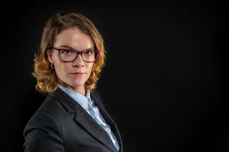 Beautiful elegant woman in a business suit and glasses on a black background