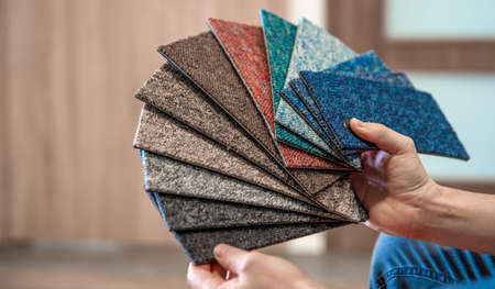the man chooses the color of the new carpet according to the pattern book in the flooring shop