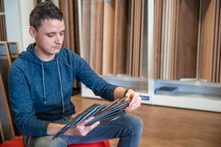 the man chooses the color of the new carpet according to the pattern book in the flooring shopの写真素材