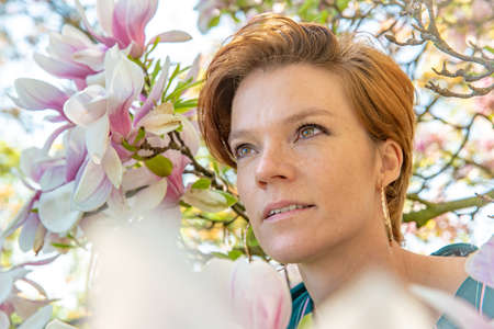 Portrait of young woman near blooming magnoliaの写真素材