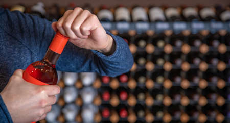 the man opens a bottle of wine with a screw-on closure at the taster in the show roomの写真素材