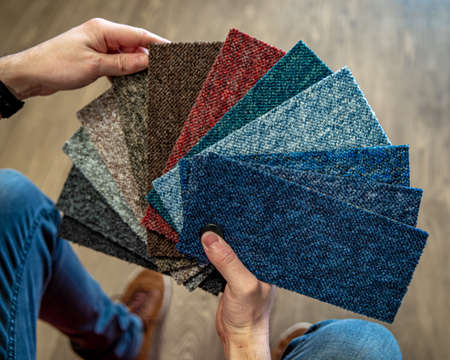 the man chooses the color of the new carpet according to the pattern book in the flooring shopの写真素材
