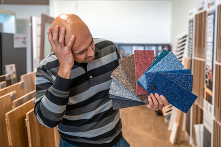 the man chooses the color of the new carpet according to the samples in the flooring shopの写真素材