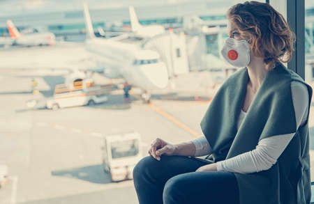 woman waiting for check-in in the airport lobby. The use of respirators for protection against virusesの写真素材