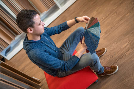 the man chooses the color of the new carpet according to the pattern book in the flooring shopの写真素材