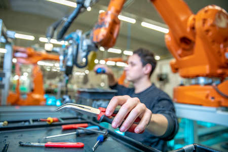 Technical worker performs maintenance robotic arms on the production line