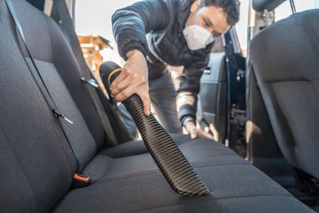 vacuuming the interior of a car with a respirator on the face during a coronavirus epidemicの写真素材