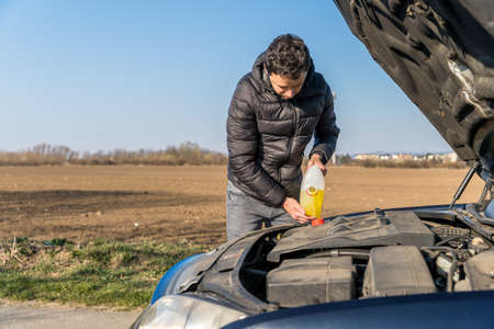 man pours into the car yellow liquid for the wiper.の写真素材