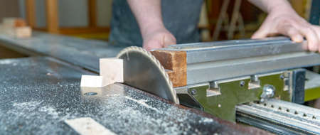 carpenter cuts wooden plank on circular saw.