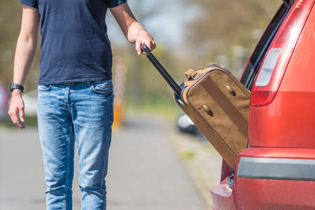 suitcase in hand, the young man pulled from the trunk passenger automobile.の写真素材