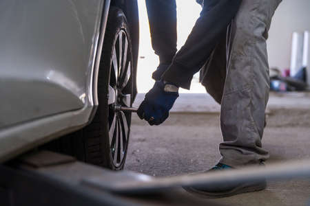 screwing the wheel to the car using a torque wrench. Replacement of seasonal tires in a car repair...
