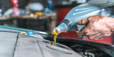 pouring new oil into the car engine from the canister during replacement.の写真素材