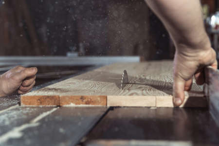A man cuts wood on a circular saw in a joineryの写真素材