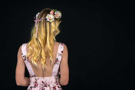 back of a young woman in a dress with golden hair. portrait on a black background whith copy spaceの写真素材